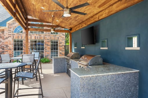 a covered patio with a grill and a table with chairs at Aston at Cinco Ranch, Texas