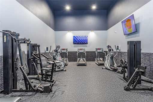 A gym with a variety of exercise equipment including treadmills, stationary bikes, and weight machines.