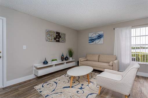 A living room with a white couch, a white coffee table, and a white chair.