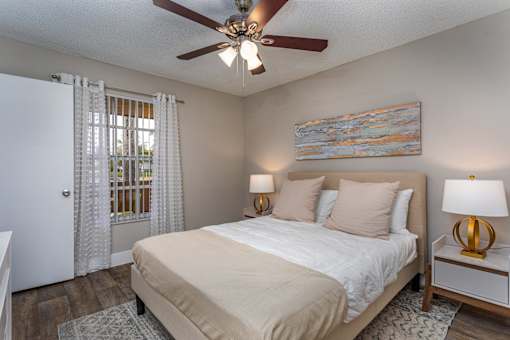 A bedroom with a bed, two lamps, and a painting on the wall.