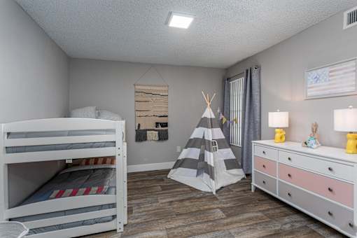 A child's bedroom with a bunk bed, a teepee, and a dresser.