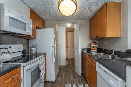 A kitchen with white appliances and wooden cabinets.