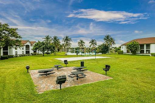 A park with a grassy area, benches, and a brick pathway.