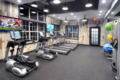 a gym with treadmills and weights and a tv at Willowest in Lindbergh, Georgia
