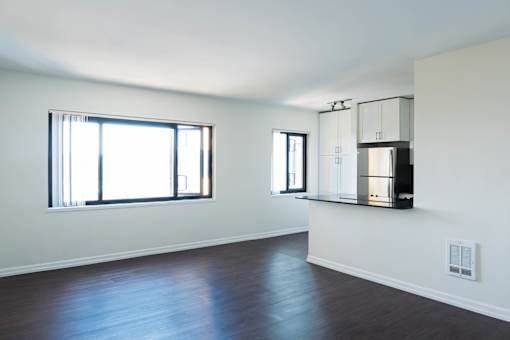 A large empty room with wooden floors and a large window at Skye at Belltown Apartments, Seattle, WA 98121