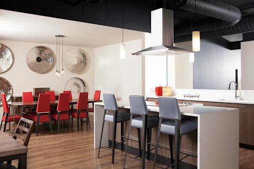 A modern kitchen with a bar area and chairs at Skye at Belltown Apartments, Washington