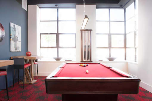 A pool table is in the middle of a room with a bar and a window at Skye at Belltown Apartments, Washington 98121