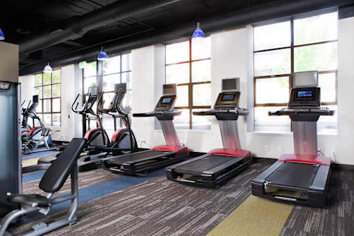 A gym with treadmills, elliptical machines, and other cardio equipment at Skye at Belltown Apartments, Seattle