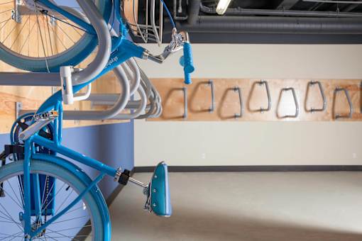 A blue bicycle is parked in front of a wall with bike racks at Skye at Belltown Apartments, Seattle