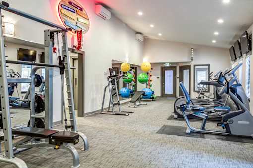 A gym with a variety of equipment including treadmills, weights, and exercise balls at Brackett Apartments, Edmonds, WA
