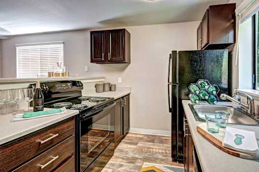 A kitchen with a black refrigerator and wooden cabinets at Brackett Apartments, Edmonds, WA, 98020