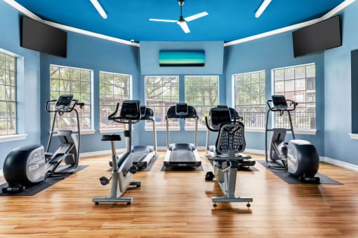 a gym with cardio equipment and windows at Villages of Cypress Creek, Houston, TX