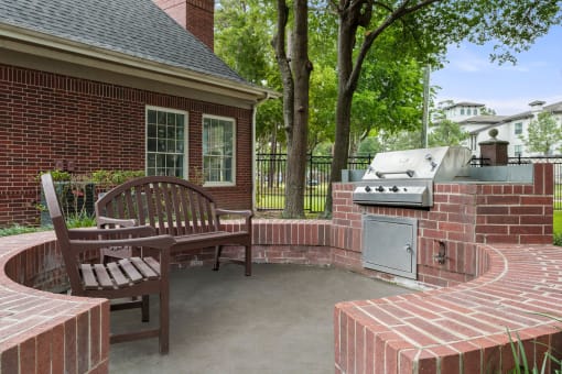 a brick patio with a barbecue grill and a wooden bench at Villages of Cypress Creek, Houston, 77070