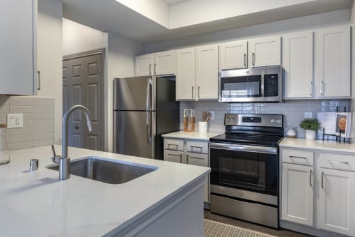 a kitchen with white cabinets and stainless steel appliances at Lakeshore at Preston, Plano, TX