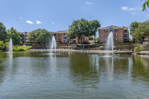 a fountain in the middle of a lake with buildings in the background at Lakeshore at Preston, Plano, 75093