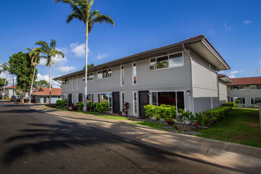 a building with palm trees in front of it on a street at MALA GROVE Apartments, Waipahu, 96797