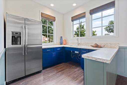 A modern kitchen with a stainless steel refrigerator and blue cabinets.