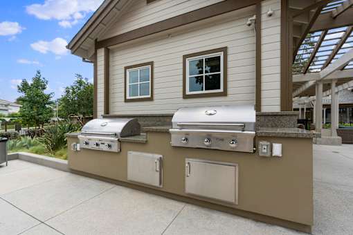 A beige outdoor kitchen with a grill and sink.