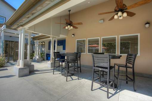 A patio with a table and chairs and a ceiling fan.