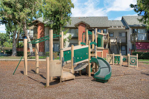 A playground with a green slide and wooden play structures.
