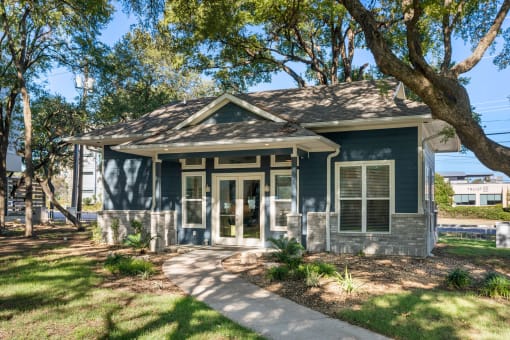 a small house with a sidewalk and trees in front of it at South Lamar Village, Austin, Texas