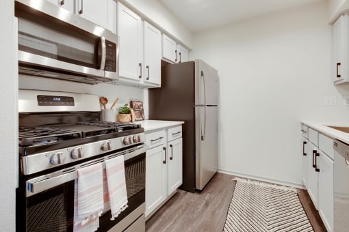 a kitchen with stainless steel appliances and white cabinets at The Olivine, Austin, 78727