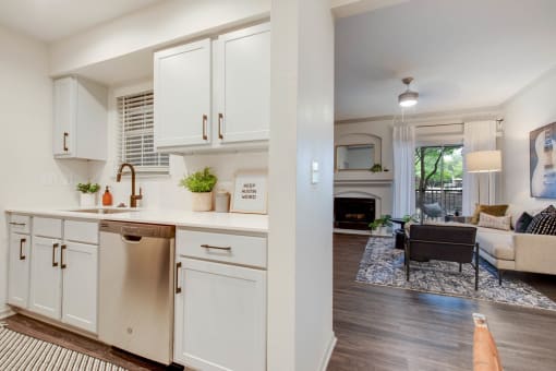 a kitchen with white cabinets and a living room with a couch at The Olivine, Austin, 78727