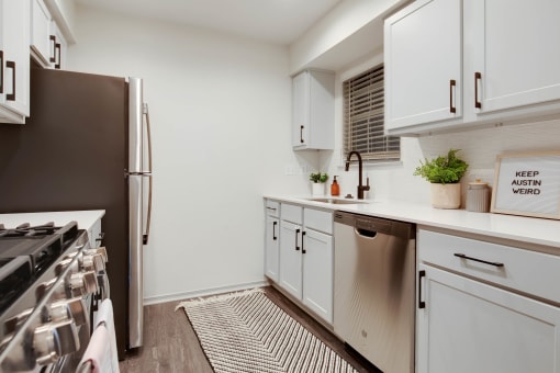 a kitchen with white cabinets and a stainless steel refrigerator at The Olivine, Austin, 78727