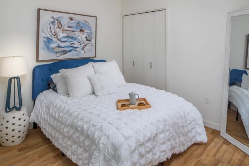 a bedroom with white walls and a blue headboard at The Parker Apartments, Oregon, 97209