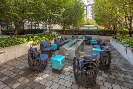 a seating area with wicker chairs and blue tables on a brick patio at The Parker Apartments, Portland, OR, 97209