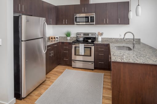 a kitchen with stainless steel appliances and granite countertops at The Parker Apartments, Portland, OR