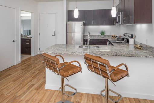 a kitchen with an island and two bar stools in front of it at The Parker Apartments, Portland, 97209
