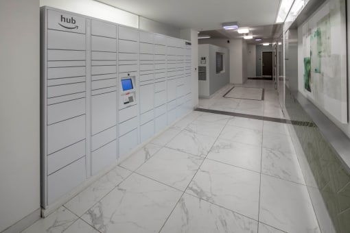a photo of a long white hallway with white marble floors and white lockers with a blue at The Parker Apartments, Oregon, 97209