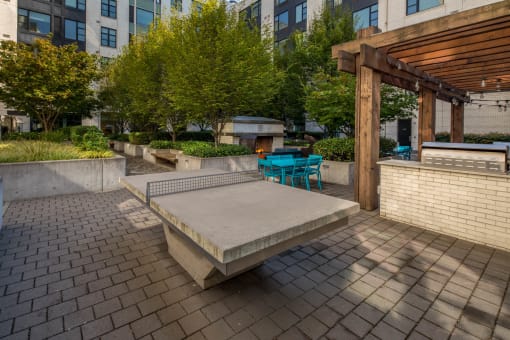 an outdoor seating area with a concrete bench and a wooden pergola at The Parker Apartments, Oregon