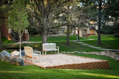 a stone patio with two chairs and a bench in a yard at Verdant, Boulder