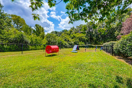 Fenced dog park with agility equipment and play structures at Wyndchase Aspen Grove Apartments, Franklin, TN
