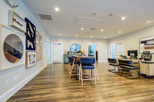 A spacious room with wooden floors and a bar area.