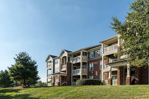 Three story brick apartment building on grassy hillside at Wyndchase Aspen Grove Apartments, Franklin