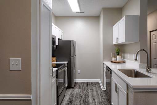 Galley kitchen with stainless steel appliances and white countertops at Wyndchase Aspen Grove Apartments, Franklin