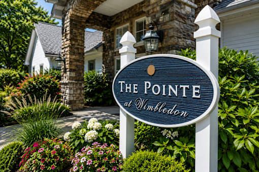 A sign that says "The Pointe at Wimbledon" in front of a house.