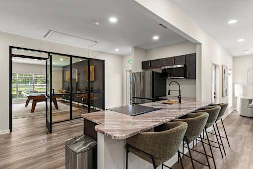 A modern kitchen with a marble countertop and a dining table with chairs.