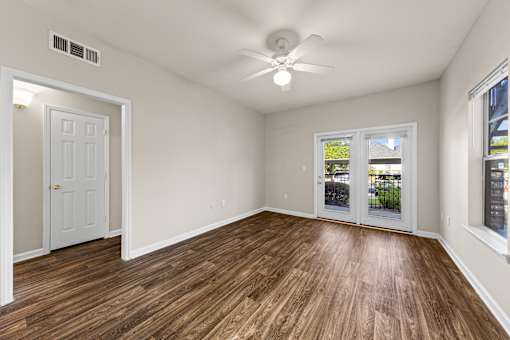 A room with a ceiling fan and wooden flooring.