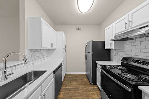 A kitchen with black appliances and white cabinets.