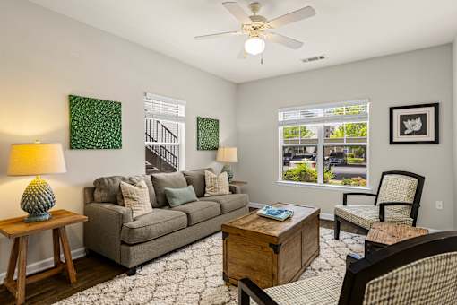 A living room with a grey couch, a wooden coffee table, and a ceiling fan.