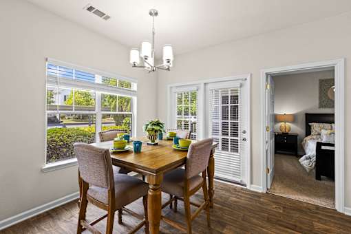 A dining room with a table and chairs and a view of the backyard.