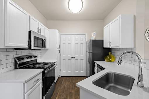A kitchen with white cabinets and a black refrigerator.