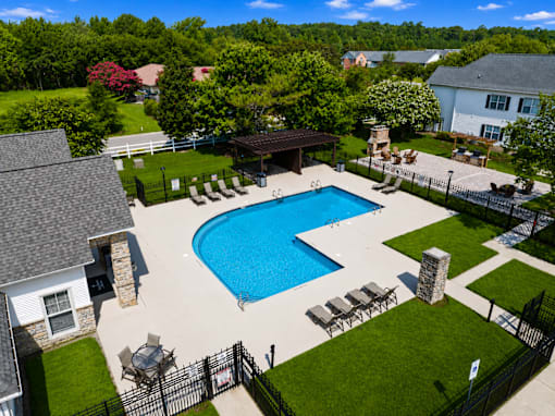 A large swimming pool surrounded by a black fence and lounge chairs.