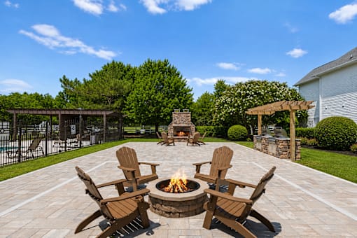 A fire pit in the middle of a patio surrounded by chairs.