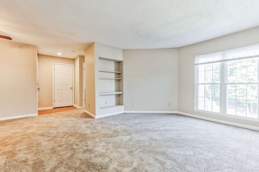 an empty living room with a large window and a closet