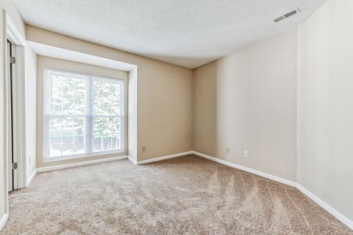 an empty living room with a large window and carpet